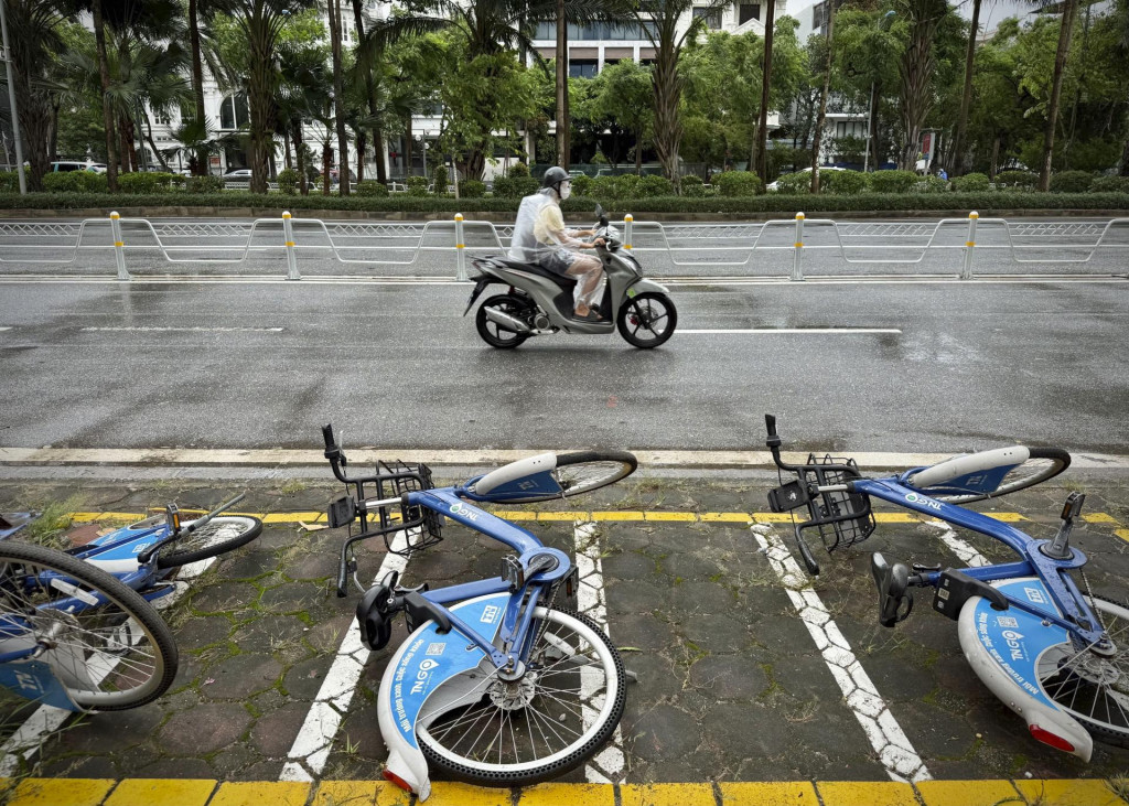 Motocyklista jazdí v daždi okolo spadnutých bicyklov po búrke Wipha v Hanoji. FOTO: TASR/AP