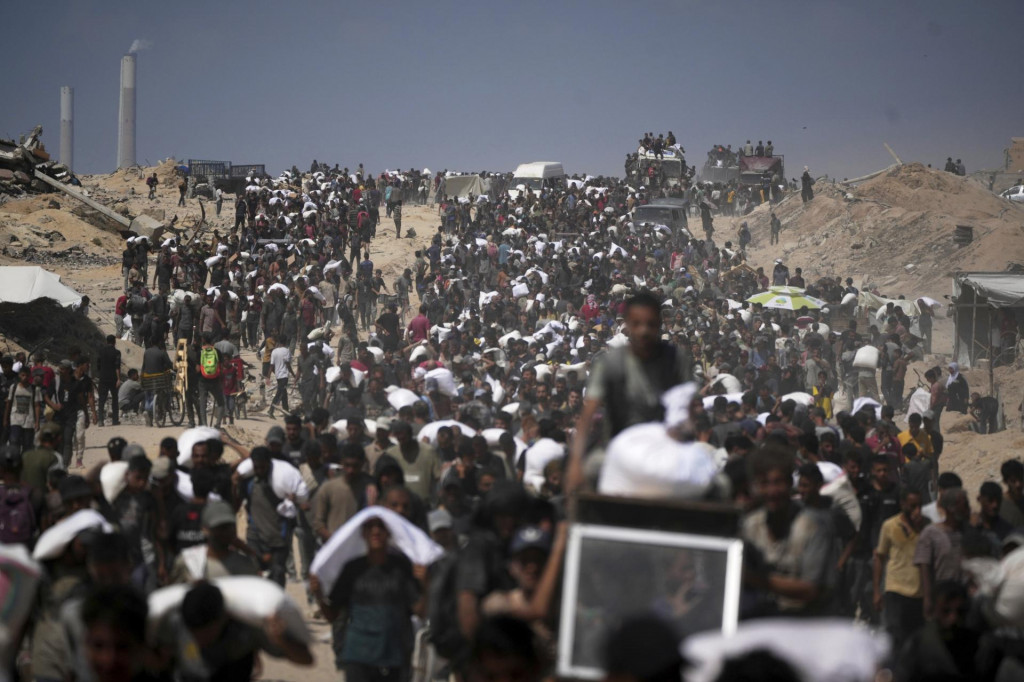 Palestínčania nesú vrecia s múkou z konvoja s humanitárnou pomocou na ceste do mesta Gaza na predmestí Bejt Lahíja na severe pásma Gazy v piatok 1. augusta 2025. FOTO: TASR/AP