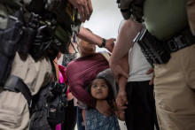 Dieťa hľadí na federálnych imigračných úradníkov, zatiaľ čo jeho otec je zadržaný na americkom imigračnom súde. FOTO: Reuters