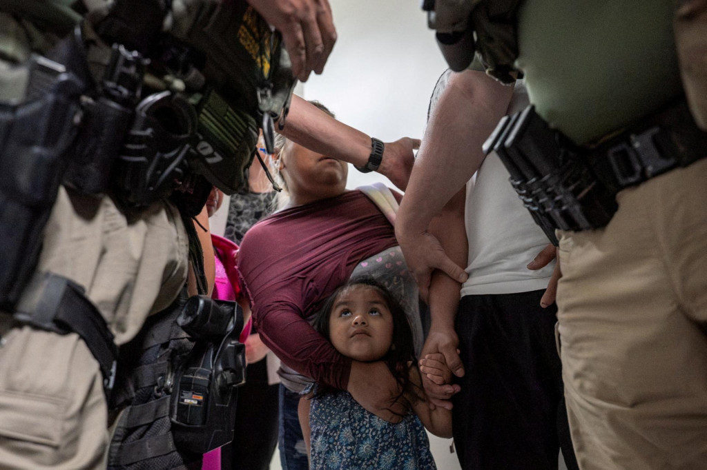 Dieťa hľadí na federálnych imigračných úradníkov, zatiaľ čo jeho otec je zadržaný na americkom imigračnom súde. FOTO: Reuters
