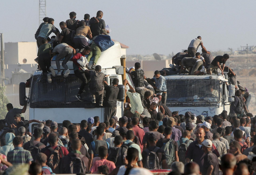 Palestínčania nastupujú do nákladných áut pri hľadaní humanitárnej pomoci v Chán Júnise v južnom Pásme Gazy. FOTO: Reuters