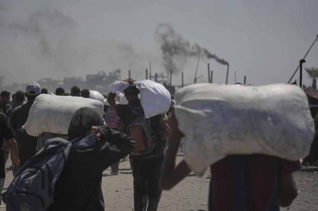 Palestínčania si odnášajú vrecia s múkou, ktoré priviezli kamióny s humanitárnou pomocou do mesta Gaza. FOTO: TASR/AP