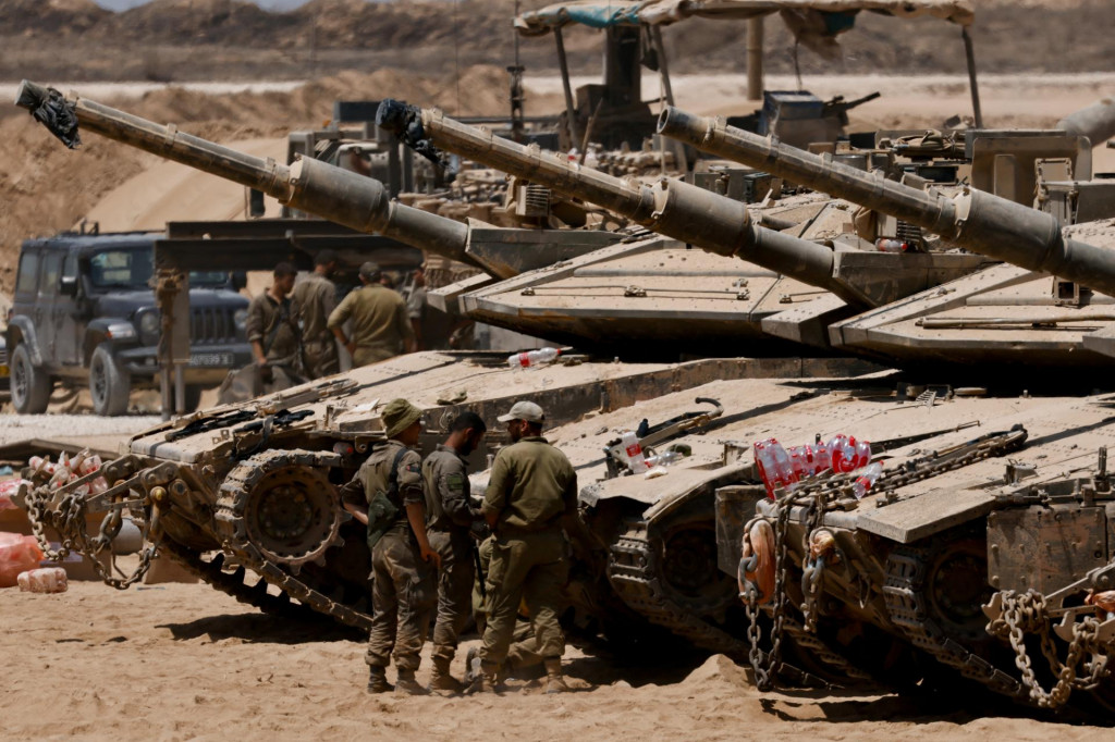 Izraelskí vojaci pracujú na svojich tankoch blízko hranice medzi Izraelom a Gazou. FOTO: Reuters