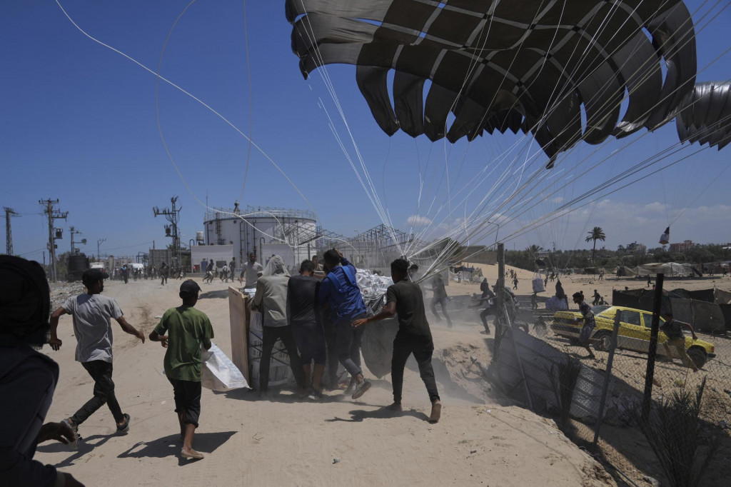 Palestínčania sa ponáhľajú po humanitárnu pomoc, ktorá bola zhodená padákmi do Dajr al-Balahu v centrálnej časti Pásma Gazy. FOTO: TASR/AP