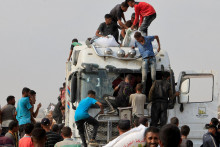 Palestínčania sa snažia vyzdvihnúť humanitárnu pomoc z kamiónov, ktoré prišli cez Izrael. FOTO: Reuters