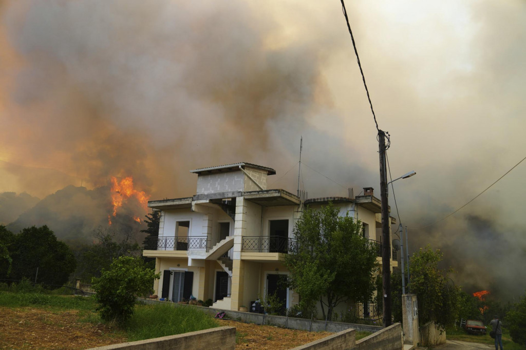 Plamene sa približujú k domu počas lesného požiaru v dedine Vounteni na predmestí mesta Patras, v západnom Grécku. FOTO: TASR/AP