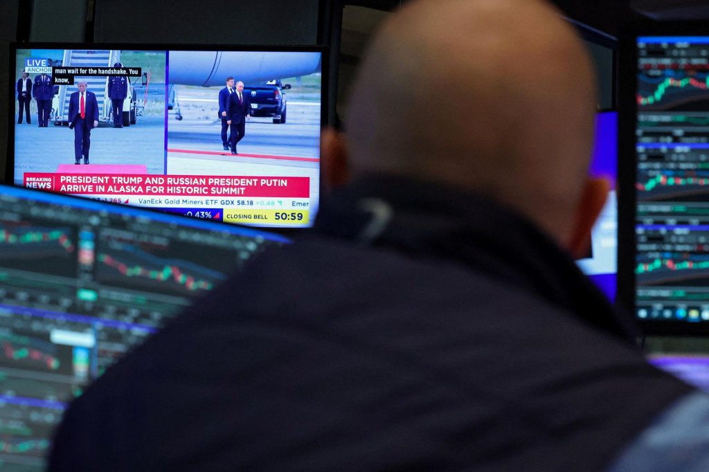 Obchodník sleduje, ako americký prezident Donald Trump víta ruského prezidenta Vladimira Putina. FOTO: Reuters