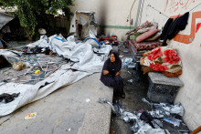 Palestínska žena sedí na mieste piatkového izraelského útoku na školu, ktorá poskytovala útočisko vysídleným osobám v meste Gaza. FOTO: Reuters