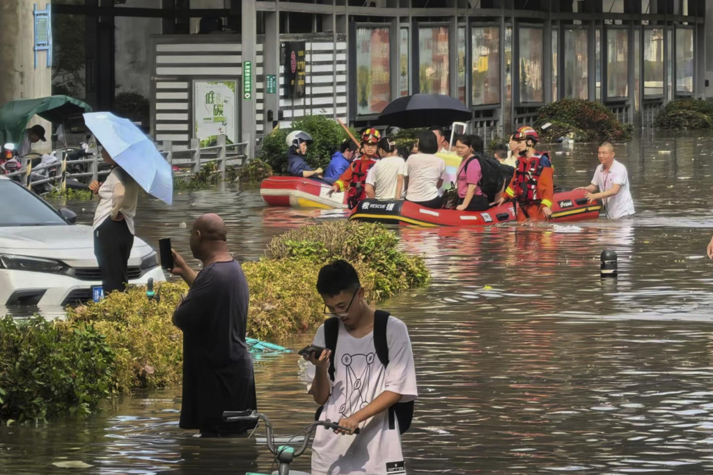 Záchranári evakuujú ľudí na nafukovacích člnoch po silných dažďoch v meste Čeng-čou v provincii Che-nan v strednej Číne. FOTO: TASR/AP