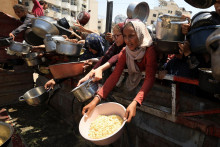 Palestínčania čakajú na jedlo z charitatívnej kuchyne v meste Gaza. FOTO: Reuters