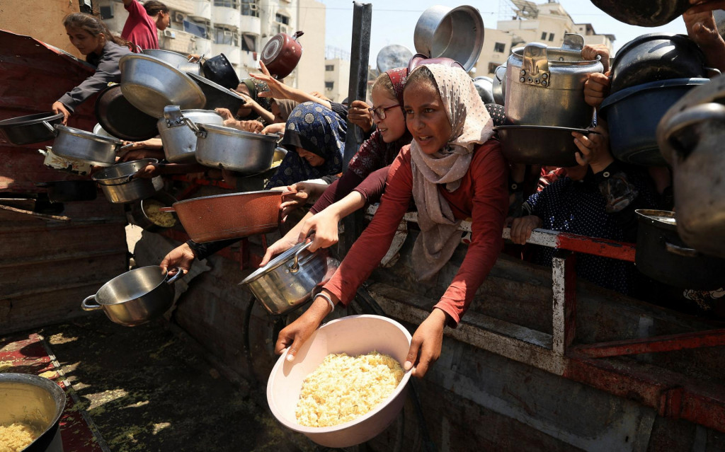 Palestínčania čakajú na jedlo z charitatívnej kuchyne v meste Gaza. FOTO: Reuters