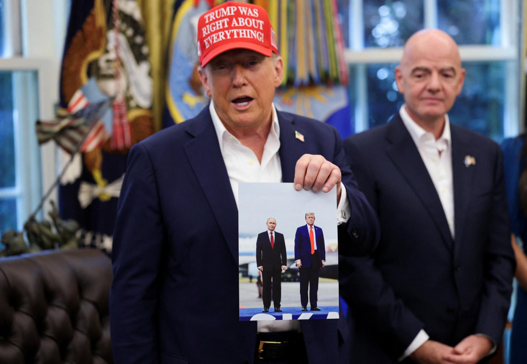 Americký prezident Donald Trump drží v ruke fotografiu seba a ruského prezidenta Vladimira Putina zo stretnutia na Aljaške. FOTO: Reuters