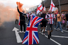 Protestujúci nesú vlajky a dymovnicu počas protiimigračnej demonštrácie. FOTO: Reuters