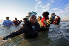 Migranti sa brodia morom v snahe dostať sa na nafukovací čln, ktorý opúšťa pobrežie severného Francúzska a prechádza cez Lamanšský prieliv. FOTO: Reuters