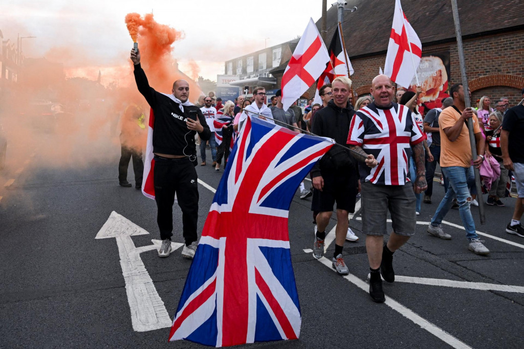 Protestujúci nesú vlajky a dymovnicu počas protiimigračnej demonštrácie. FOTO: Reuters