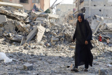 Žena kráča po mieste nočného izraelského útoku na dom v meste Gaza. FOTO: Reuters