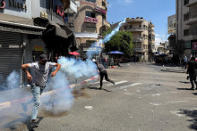 Palestínsky muž odhadzuje plynový granát počas stretov s izraelskými jednotkami po razii v Ramalláhu na Izraelom okupovanom Západnom brehu Jordánu. FOTO: Reuters