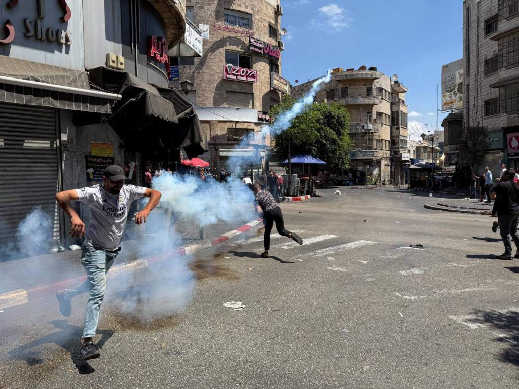 Palestínsky muž odhadzuje plynový granát počas stretov s izraelskými jednotkami po razii v Ramalláhu na Izraelom okupovanom Západnom brehu Jordánu. FOTO: Reuters