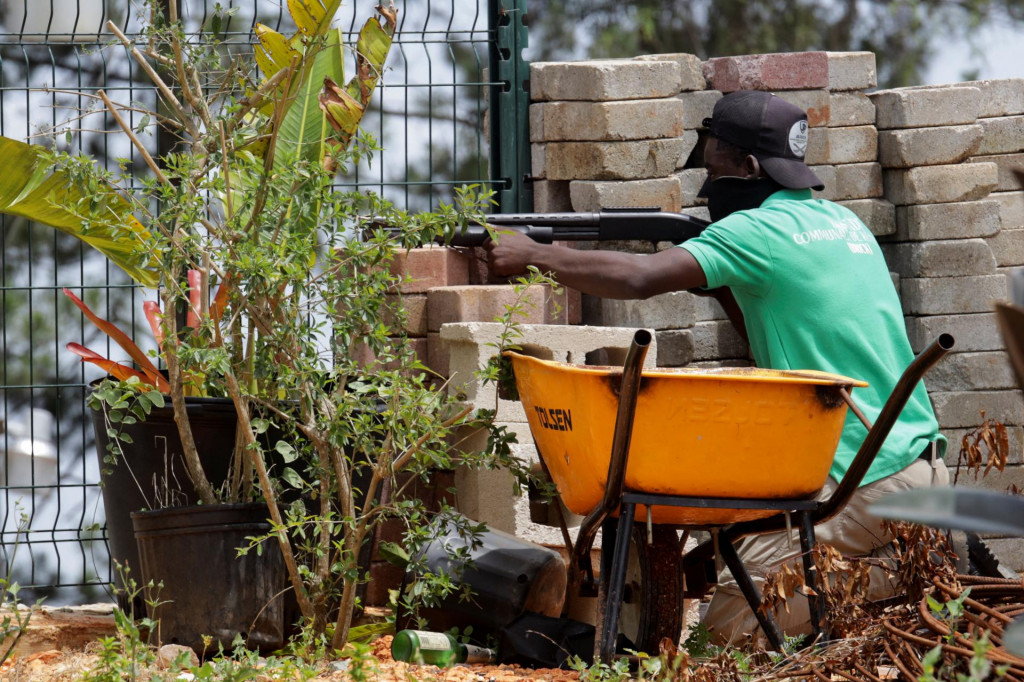 Príslušník bezpečnostných síl komunity zaujíma pozíciu za múrom, zatiaľ čo po operácii haitskej národnej polície a mnohonárodnej bezpečnostnej misie na opätovné dobytie komunikačného strediska Teleco a okolitej komunity z rúk ozbrojených gangov na okraji Port-au-Prince v Kenscoffe na Haiti sú počuť výstrely. FOTO: Reuters