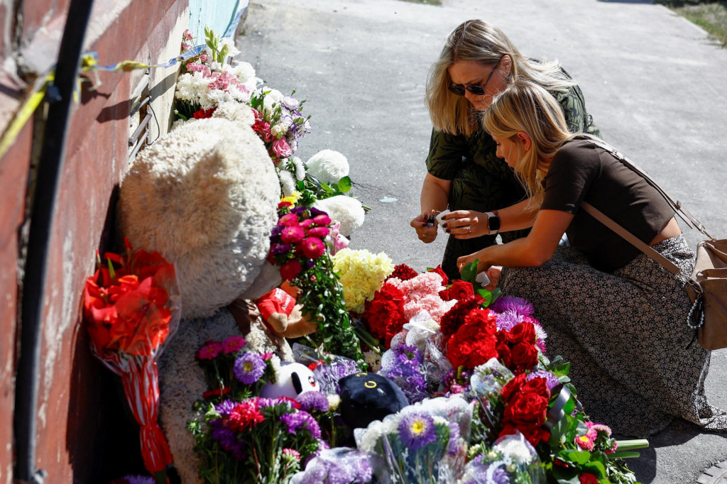 Ženy zapaľujú sviečky pri provizórnom pamätníku na mieste bytového domu, ktprý zasiahol ruský útok v Kyjeve. FOTO: Reuters