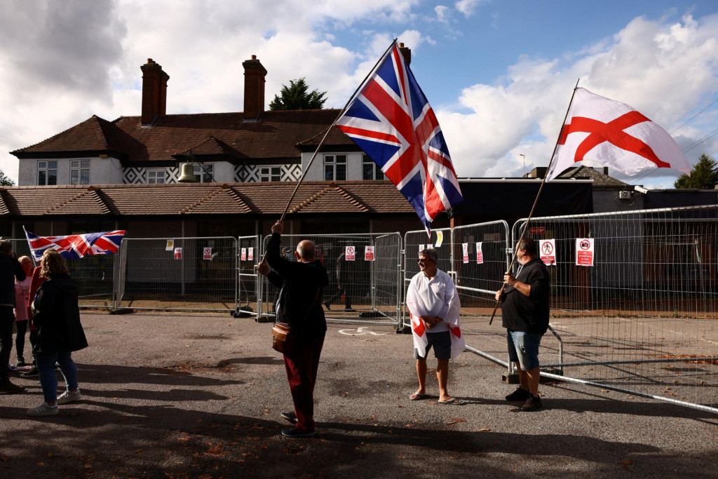 Protestujúci držia vlajky Spojeného kráľovstva a St. George pred hotelom Bell v Essexe. FOTO: Reuters