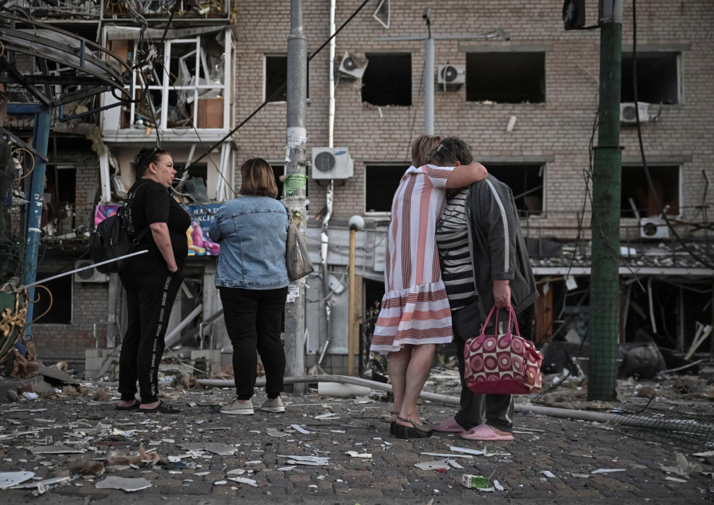 Obyvatelia stoja na mieste bytového domu zasiahnutého počas ruského útoku dronom a raketami v Záporoží. FOTO: Reuters