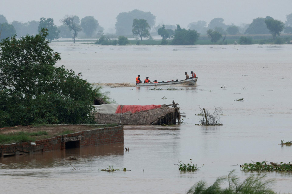 Záchranný čln evakuuje ľudí zo zaplavenej oblasti okolo čiastočne zatopených domov po monzúnových dažďoch a stúpajúcej hladine rieky v dedine Chanda Singh Wala neďaleko pakistansko-indických hraníc. FOTO: Reuters