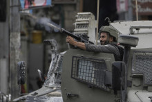 Člen izraelských bezpečnostných síl strieľa slzný plyn počas vojenského zásahu v meste Náblus na Západnom brehu Jordánu. FOTO: TASR/AP