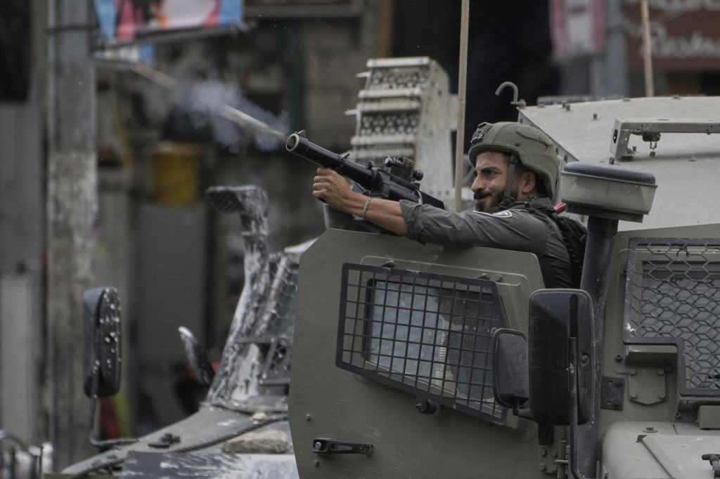 Člen izraelských bezpečnostných síl strieľa slzný plyn počas vojenského zásahu v meste Náblus na Západnom brehu Jordánu. FOTO: TASR/AP