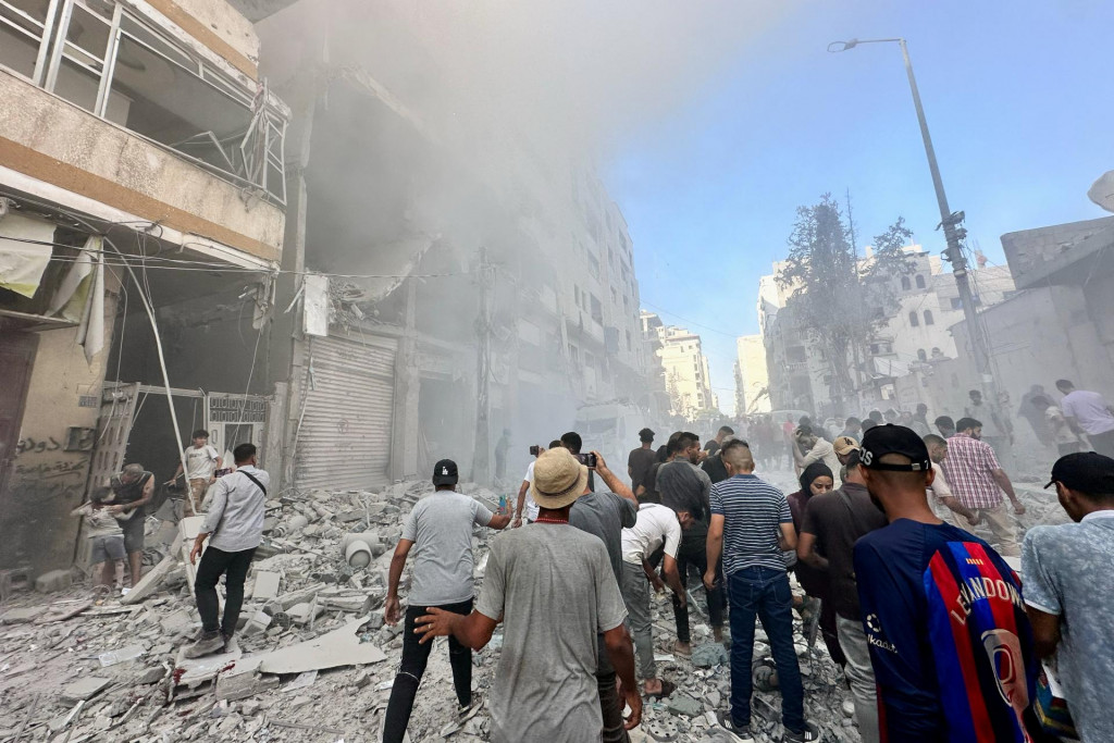 Palestínčania sa zhromažďujú na mieste izraelského útoku na obytnú budovu v meste Gaza. FOTO: Reuters