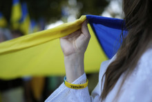 Na snímke ukrajinská žena pomáha držať vlajku. FOTO: TASR/AP