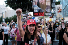Žena v červenej čiapke so žltou stuhou ukazuje podporu a rodinným príslušníkom rukojemníkov v Tel Avive. FOTO: Reuters