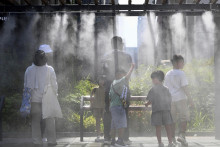 Ľudia sa schladzujú pod vodnou parou v Tokiu. FOTO: TASR/AP