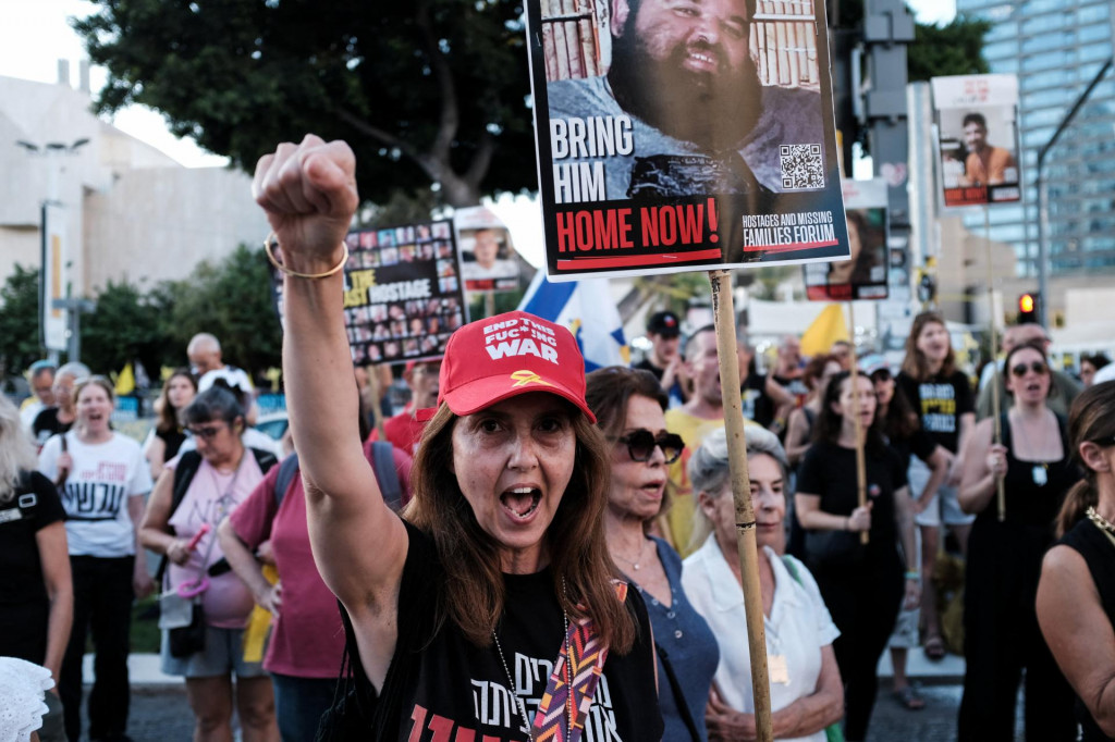 Žena v červenej čiapke so žltou stuhou ukazuje podporu a rodinným príslušníkom rukojemníkov v Tel Avive. FOTO: Reuters