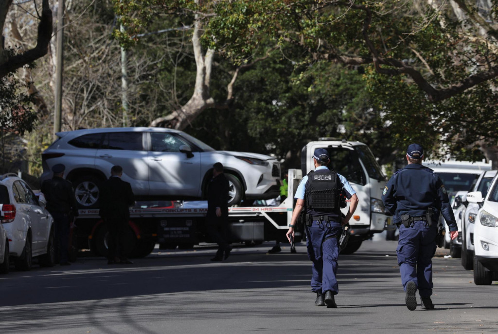 Policajti dohliadajú na nakladanie auta s rozbitým oknom po tom, čo narazilo do ruského konzulátu v Sydney. FOTO: Reuters