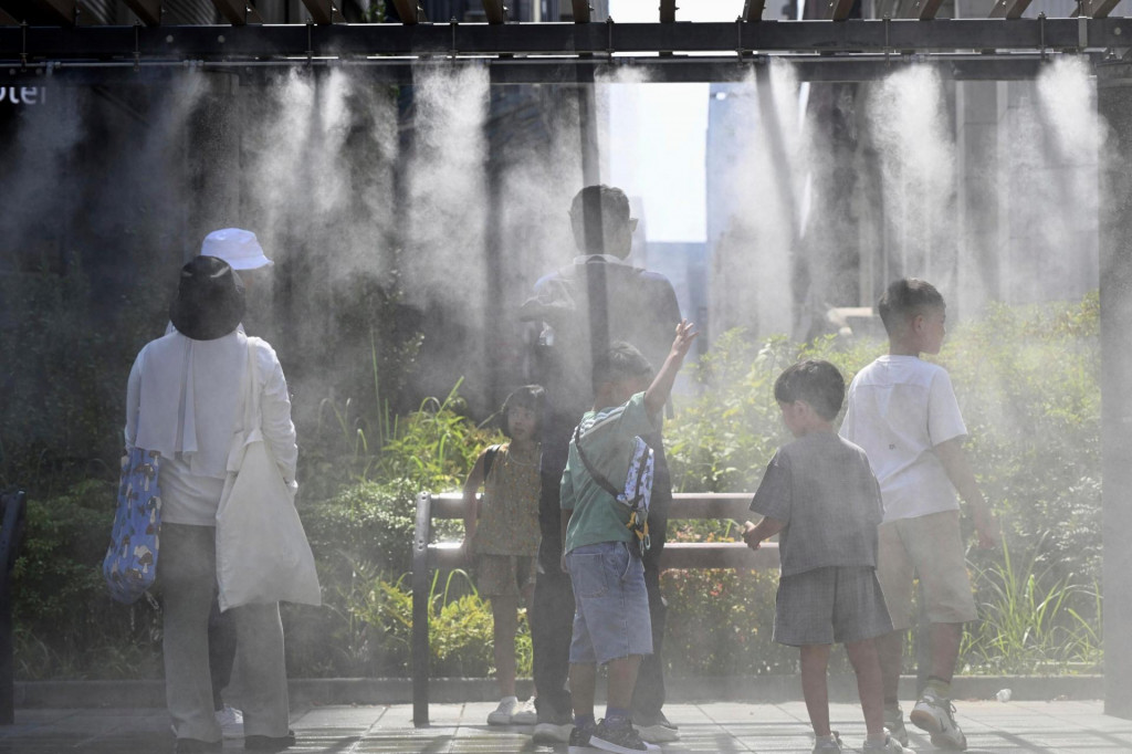 Ľudia sa schladzujú pod vodnou parou v Tokiu. FOTO: TASR/AP