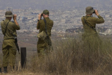 Izraelskí vojaci sa pozerajú cez ďalekohľady na zničené budovy v pásme Gazy neďaleko hranice Izraela s pásmom Gazy, čo je viditeľné z juhu Izraela. FOTO: TASR/AP