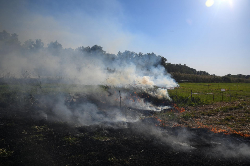 Dym z horiacej trávy stúpa na mieste humanitárnej odmínovacej misie, kde dnes podľa miestnych úradov ruský raketový útok na Ukrajinu zabil dvoch členov misie na okraji Černihivu.  FOTO: Reuters