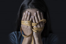 close up hands wrapped in tailor measure tape covering face of young depressed and worried girl suffering anorexia or bulimia nutrition disorder on black background obsessed with diet and overweight