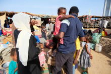 Al-Rasheed Al-Tahir, vysídlený Sudánčan, ktorý sa opäť stretáva so svojimi sestrami, synovcami a neterami, kráča a nesie deti svojej sestry, ktorá bola zabitá. FOTO: Reuters