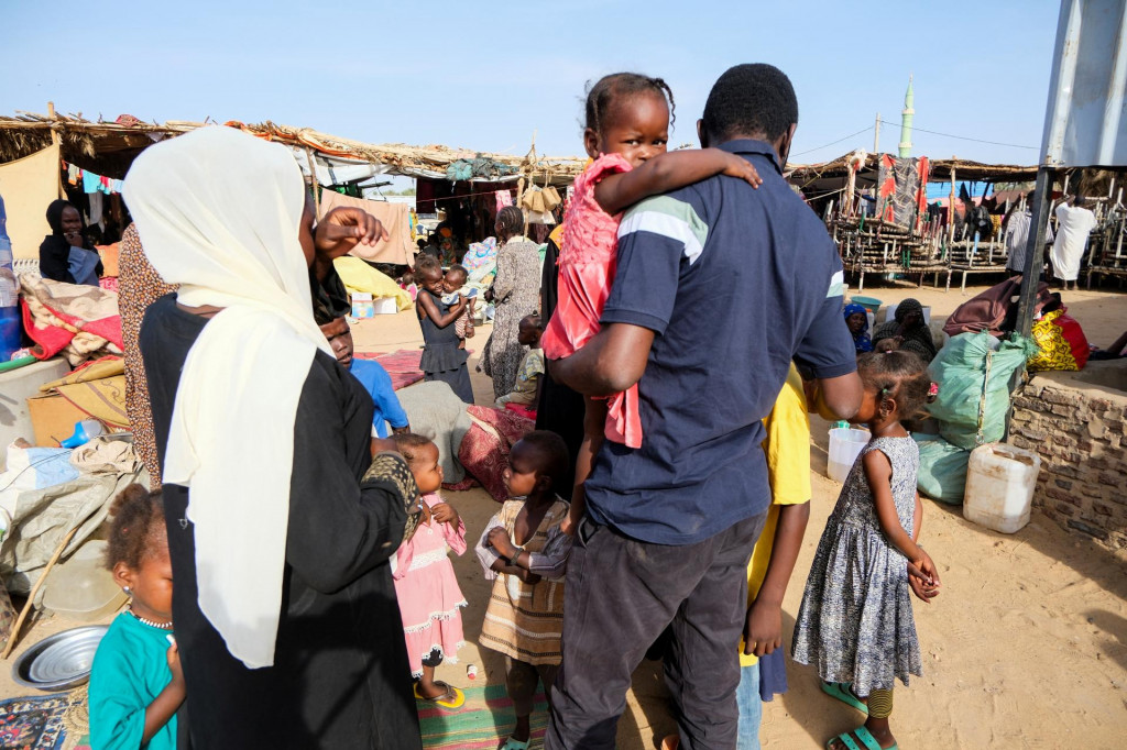 Al-Rasheed Al-Tahir, vysídlený Sudánčan, ktorý sa opäť stretáva so svojimi sestrami, synovcami a neterami, kráča a nesie deti svojej sestry, ktorá bola zabitá. FOTO: Reuters