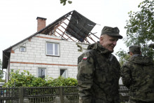 Na snímke príslušníci teritoriálnej obrany stoja pri obytnom dome, ktorého strechu poškodili úlomky jedného z ruských dronov v poľskej obci Wyryki v Lublinskom vojvodstve. FOTO: TASR/AP