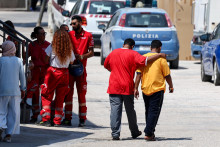 Členovia talianskeho Červeného kríža sa rozprávajú pred hotspotom, prijímacím centrom pre migrantov, na Lampeduse. FOTO: Reuters