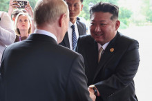 Ruský prezident Vladimir Putin (chrbtom) a severokórejský líder Kim Čong-un si podávajú ruky po stretnutí v Pekingu. FOTO: TASR/AP