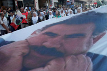 Ľudia pochodujú s transparentom s vyobrazením väzneného kurdského militantného vodcu Abdullaha Öcalana. FOTO: Reuters