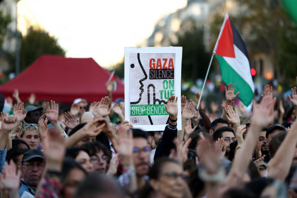 Ľudia držia transparent s nápisom „Gaza, ticho, zabíjame. Zastavme genocídu“ a palestínsku vlajku počas protestu proti izraelským operáciám v pásme Gazy na Námestí republiky v Paríži. FOTO: Reuters