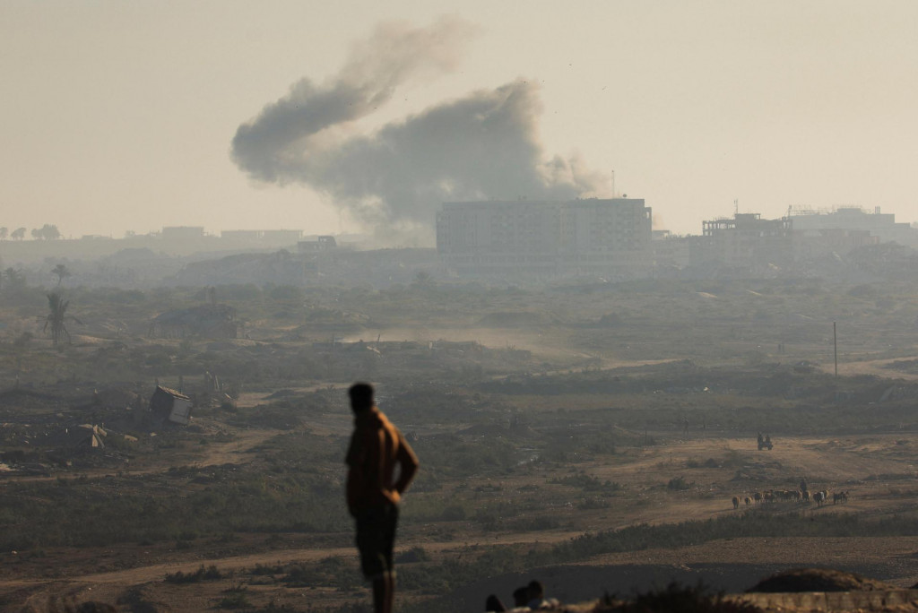 Muž sa pozerá na dym stúpajúci z izraelského útoku v Pásme Gazy. FOTO: Reuters