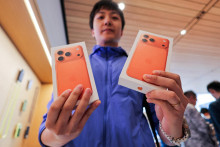 Muž ukazuje krabičky so zakúpenými smartfónmi iPhone 17 Pro.