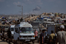 Dym stúpa nad mestom Gaza po izraelskom leteckom útoku, zatiaľčo vysídlení Palestínčania utekajú zo severného Pásma Gazy so svojimi vecami na ceste na juh cez Wadi Gazu 24. septembra 2025 po tom, ako izraelská armáda nariadila okamžitú evakuáciu celého mesta Gaza. FOTO: TASR/AP
