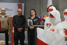 Exilová líderka bieloruskej opozície Sviatlana Cichanovská spolu s časťou prepustených väzňov (vľavo) počúva starú bieloruskú hymnu počas vystúpenia zboru so starými bieloruskými vlajkami v litovskej metropole Vilnius. FOTO: TASR/AP